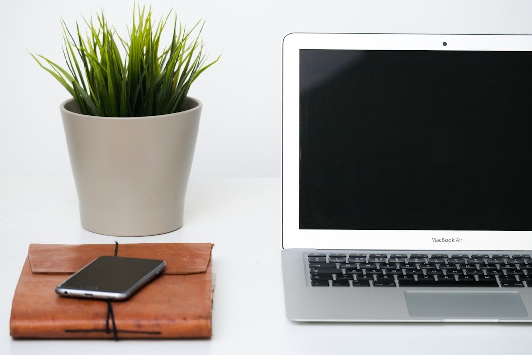 Desk with notebook, laptop and plant in a bright office
